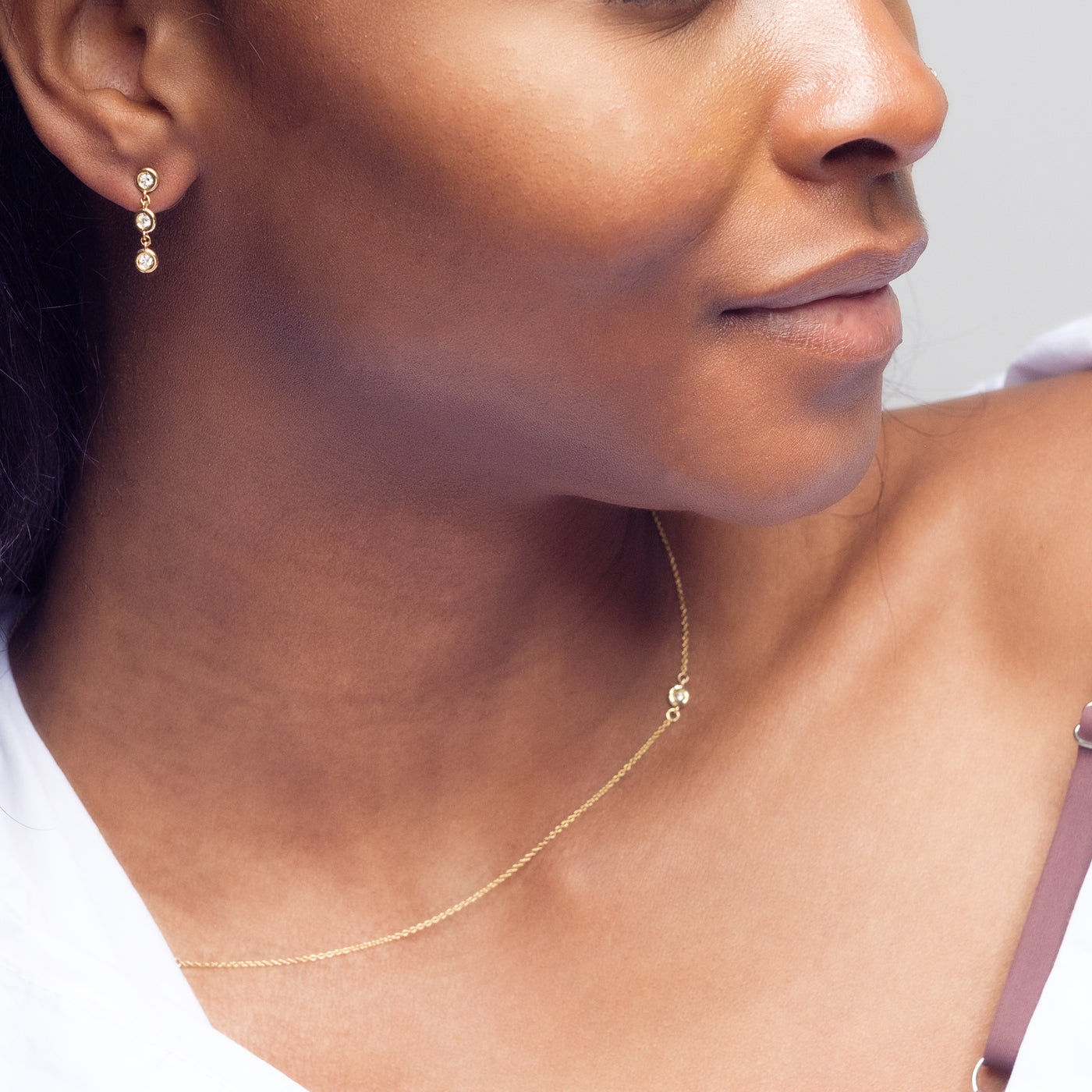 Essential Diamond Bezel Drop is a pair of earrings with 3 diamond drops each in 18kt yellow gold worn on woman