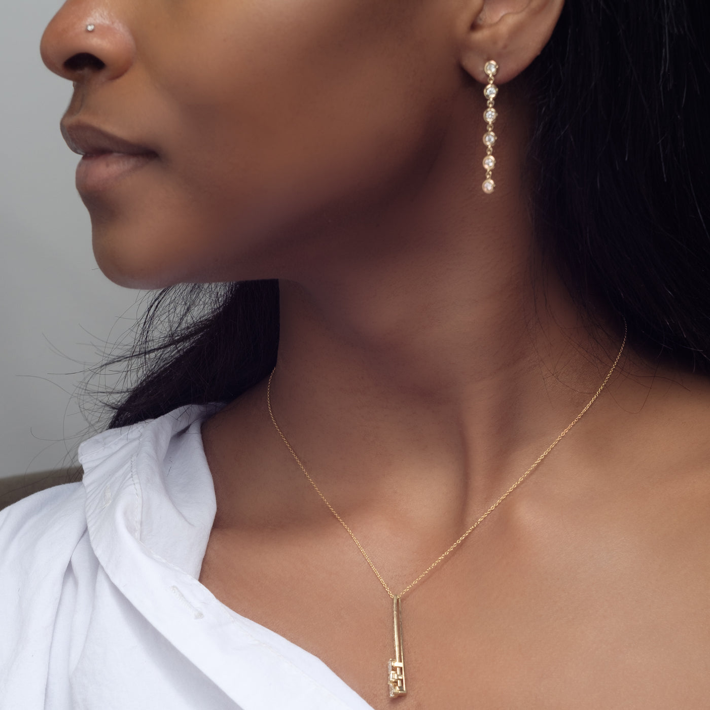 Essential Diamond Bezel Drop is a pair of earrings with 6 diamond drops each in 18kt yellow gold worn on woman