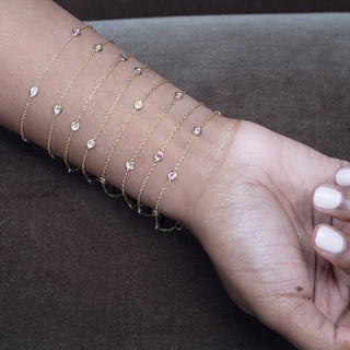 Essential Diamond Bezel Bracelet in 18kt yellow gold worn on a hand along with the Essential Diamond & Gem Bezel Bracelet in all color combinations 