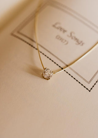 Essential Solitaire Necklace is an omega chain with a round brilliant cut diamond in 18kt yellow gold on a book. 