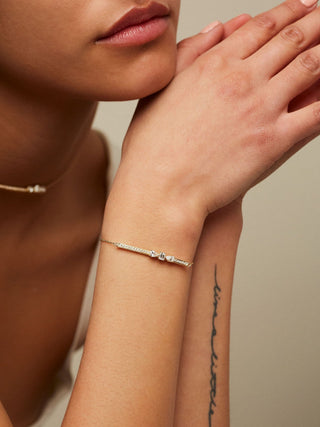 Dizzy Slide Bracelet is a bracelet with 3 diamonds sliding on a diamond line, made in 18kt yellow gold worn by woman