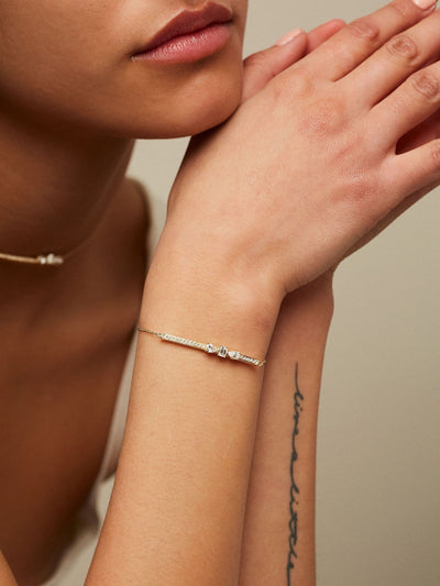 Dizzy Slide Bracelet is a bracelet with 3 diamonds sliding on a diamond line, made in 18kt yellow gold worn by woman