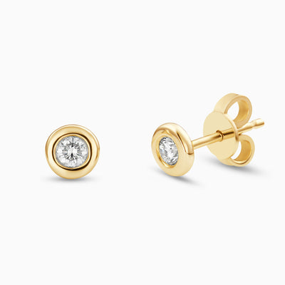 Essential Diamond Bezel Studs are diamond bezel-set studs in 18kt yellow gold