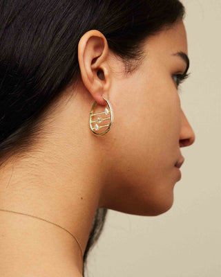 Dizzy Abacus earrings in 18kt yellow gold worn by woman